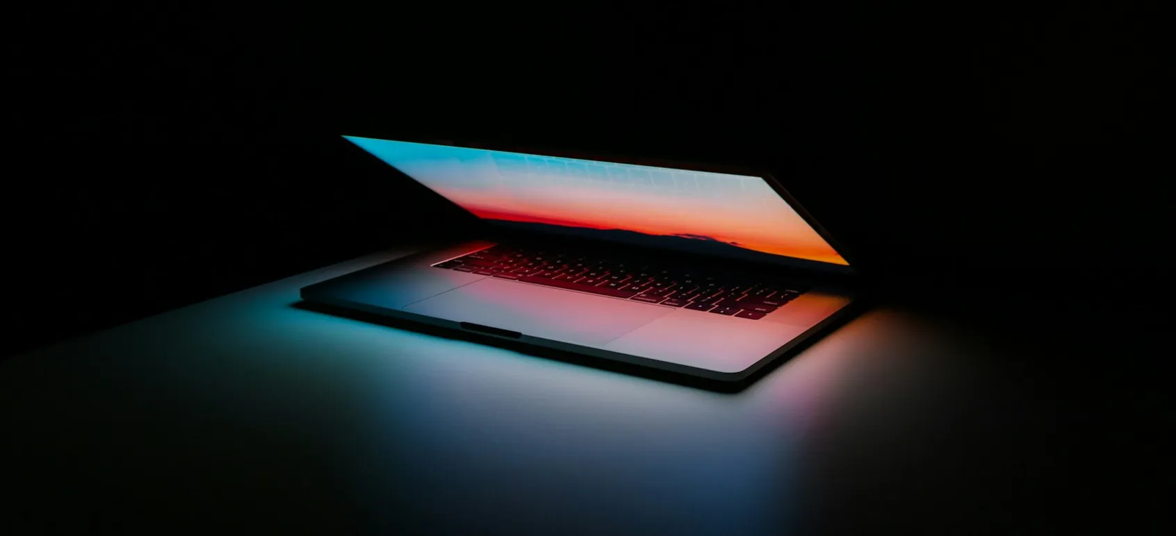 A half-open laptop glowing in a dark room